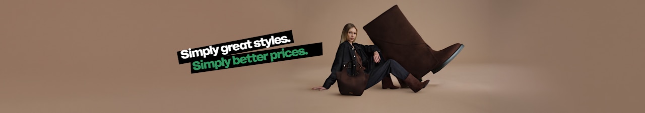 A promotional campaign image on a neutral beige background features an oversized dark brown ankle boot alongside a person wearing a dark denim outfit, matching brown ankle boots, and a dark brown handbag. English promotional text appears on the left side of the image, reading “Simply great styles. Simply better prices.” The studio composition highlights the coordinated fashion look and the featured footwear.