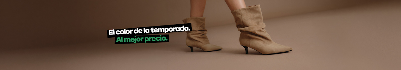 A promotional image shows a person wearing beige slouchy ankle boots against a neutral beige background. The boots feature a soft suede-like texture, pointed toes, gathered shafts, and slim kitten heels. Spanish promotional text appears on the left side of the image, including the price “34.99”.