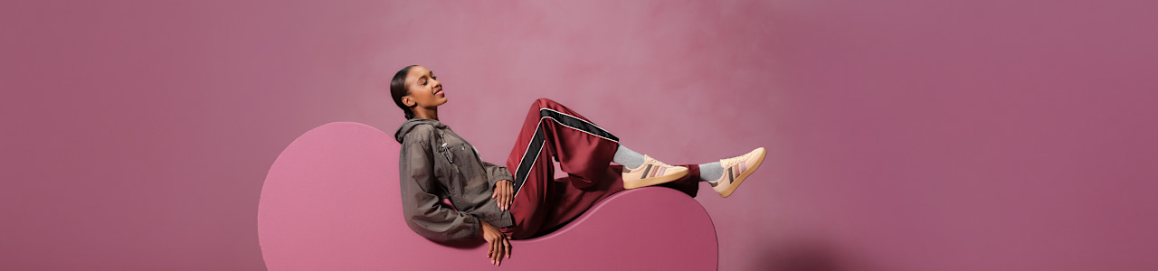 women with sneaker sitting on a pedestal with pink background