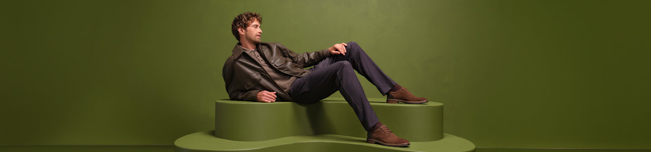 men with loafers sitting on a pedestal with green background