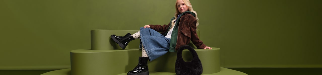 girl with boots sitting on a pedestal with green background