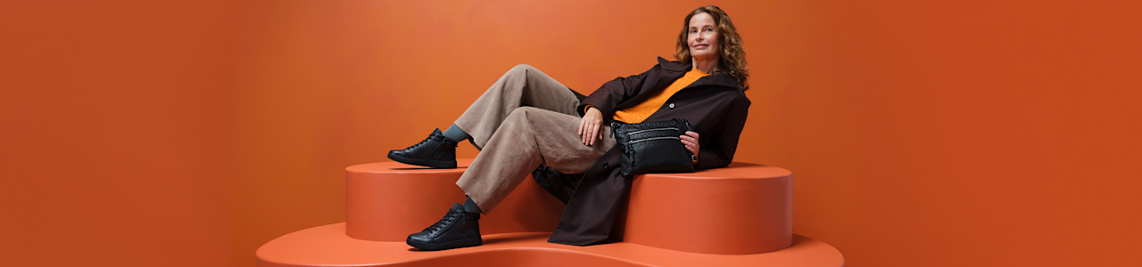 women with comfort boots sitting on a pedestal with orange background