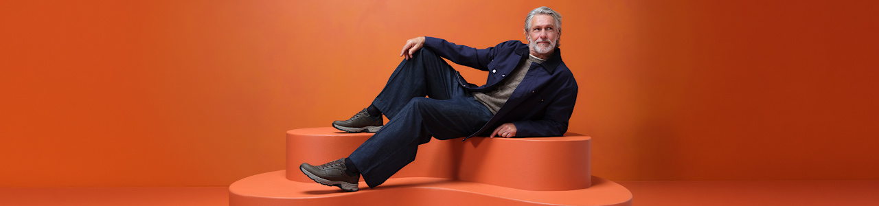 men with comfort shoes sitting on a pedestal with orange background