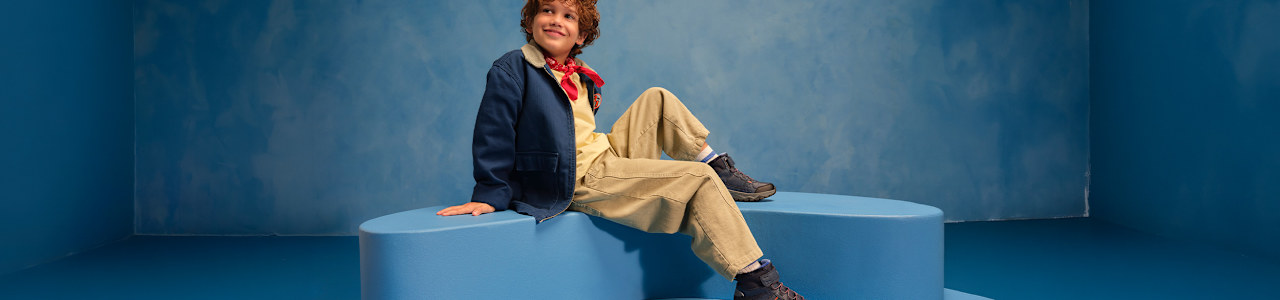 boy with boots sitting on a podest with blue background
