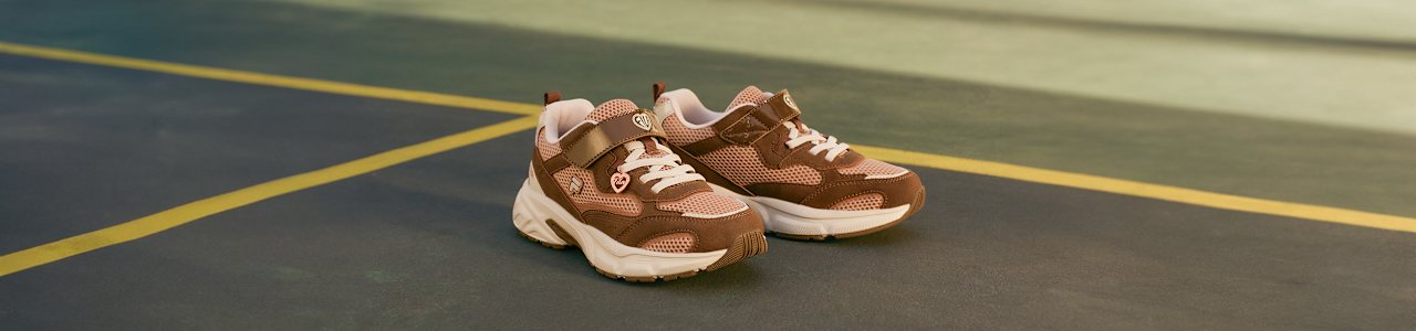 Brown sporty sneakers placed on an indoor court.