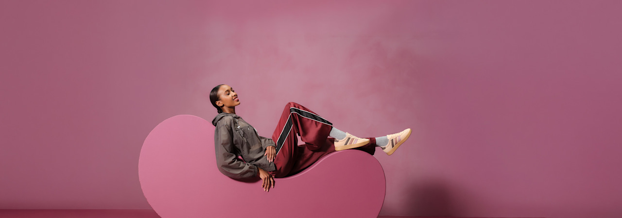 women with sneaker sitting on a pedestal with pink background