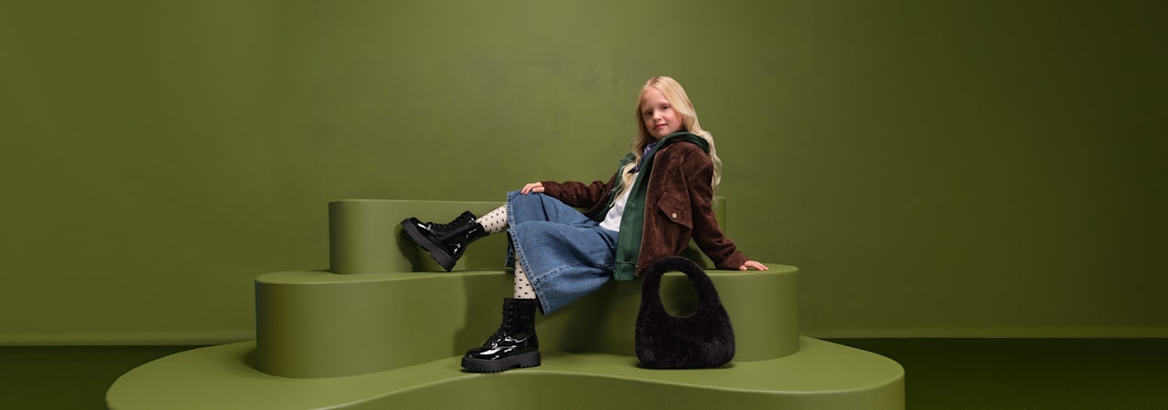 girl with boots sitting on a pedestal with green background