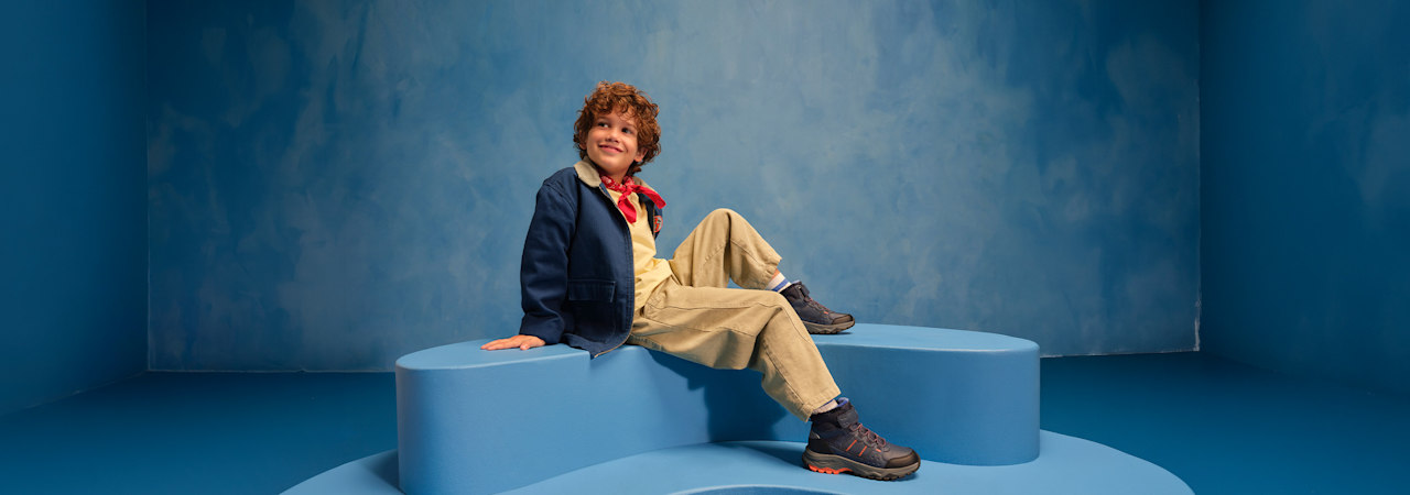 boy with boots sitting on a podest with blue background