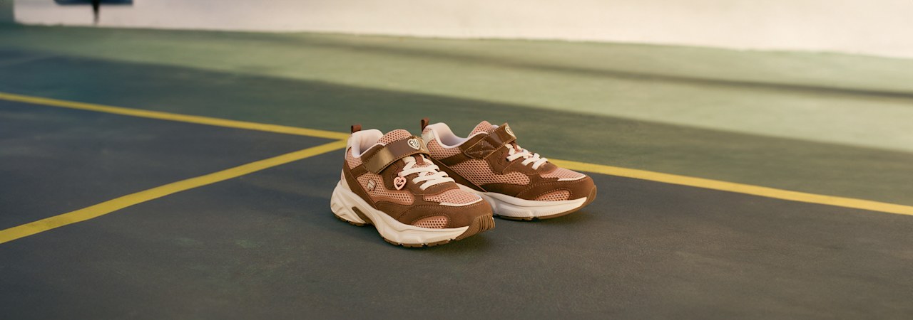 Brown sporty sneakers placed on an indoor court.