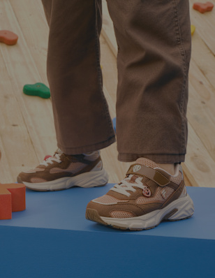 Brown sneakers worn with casual trousers.