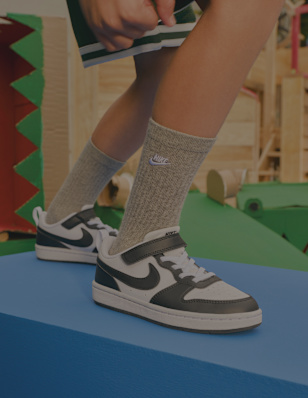 Black-and-white Nike sneakers worn with grey socks on a play structure.