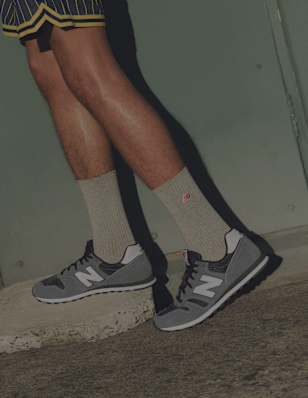 Close-up of a person wearing green socks and dark-grey sneakers on an urban background.