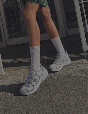 Close-up of a person wearing white socks and sneakers on an urban background.