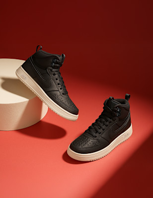 Two black Nike Mid Cut Sneaker in front of a red background