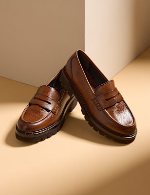 Two women's loafers in front of beige background