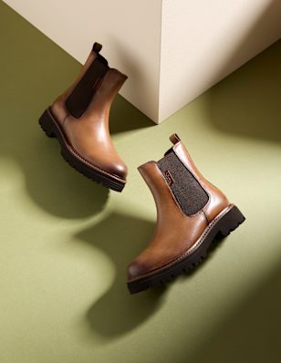 Women's chelsea boots in front of a green background