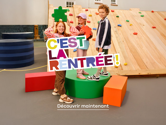 Children posing with a “C’est la rentrée!” back-to-school display.