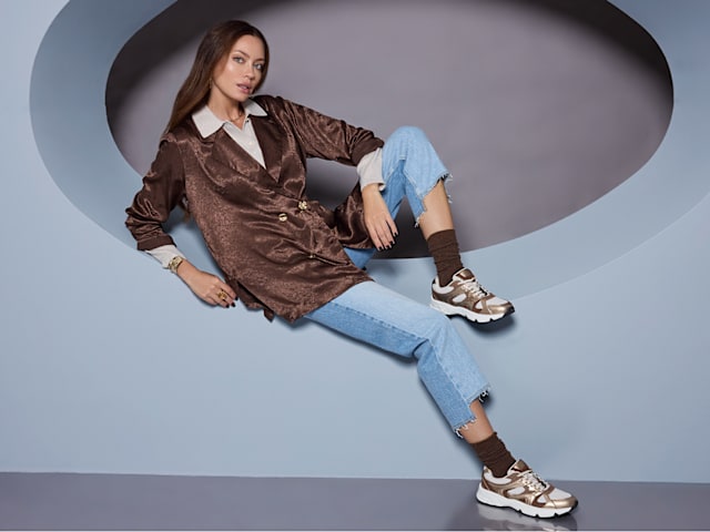 women with metallic shoes sitting on a pedestal
