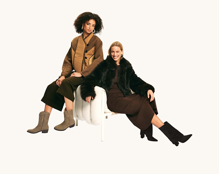Two people in western-inspired outfits posing on a white stool, wearing brown and black layered looks with boots.