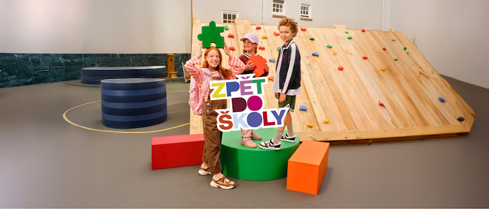 Children posing with a “Zpět do školy” (Back to School) sign.
