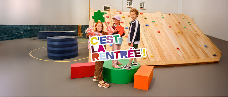 Children posing with a “C’est la rentrée!” back-to-school display.