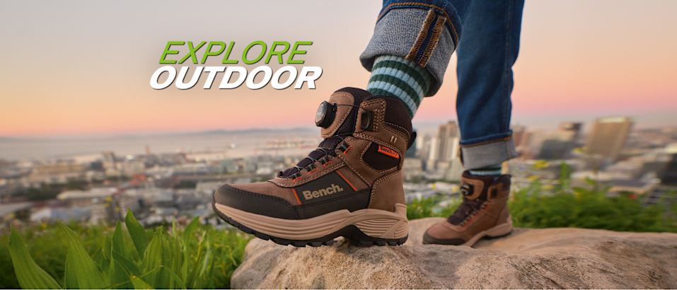 Explore Outdoor campaign visual featuring brown hiking boots overlooking a city landscape.