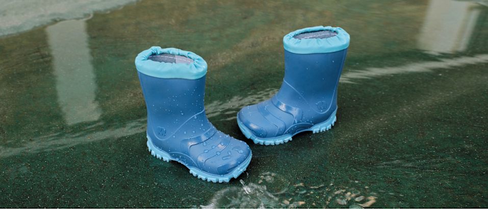 Blue waterproof rain boots standing in shallow water.