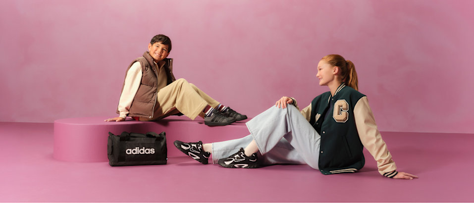 two kids with sneaker sitting on a pedestal with pink background
