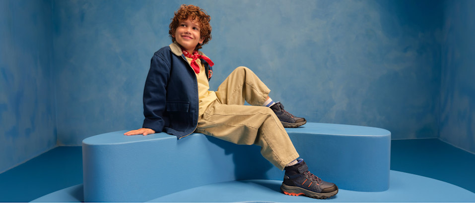 boy with boots sitting on a podest with blue background