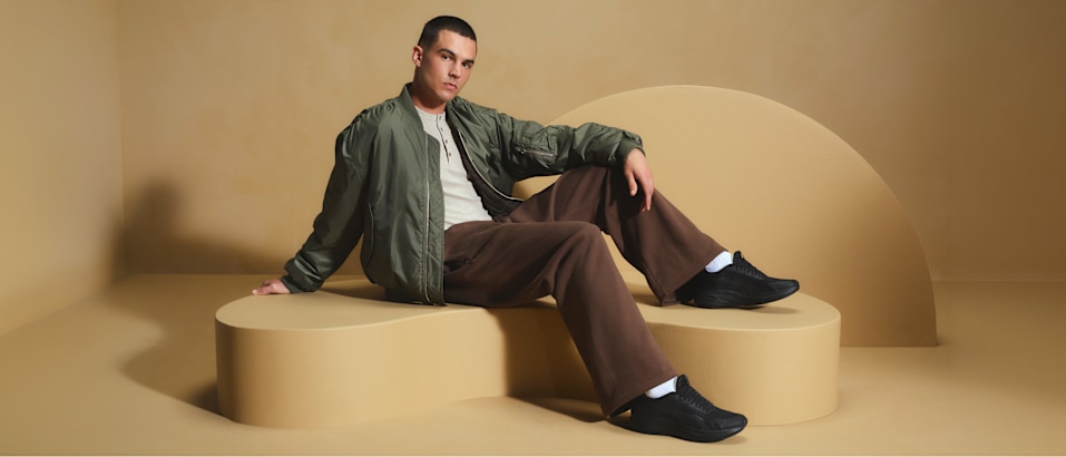 men with sneaker sitting on a pedestal with beige background