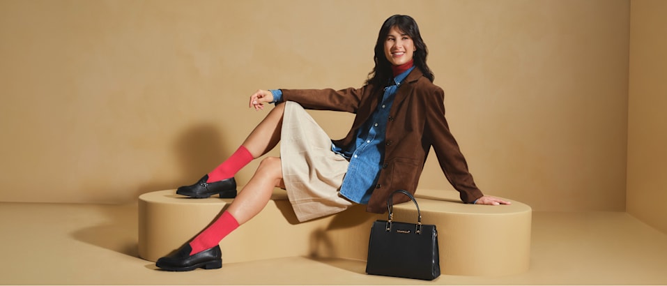women with loafers sitting on a pedestal with beige background